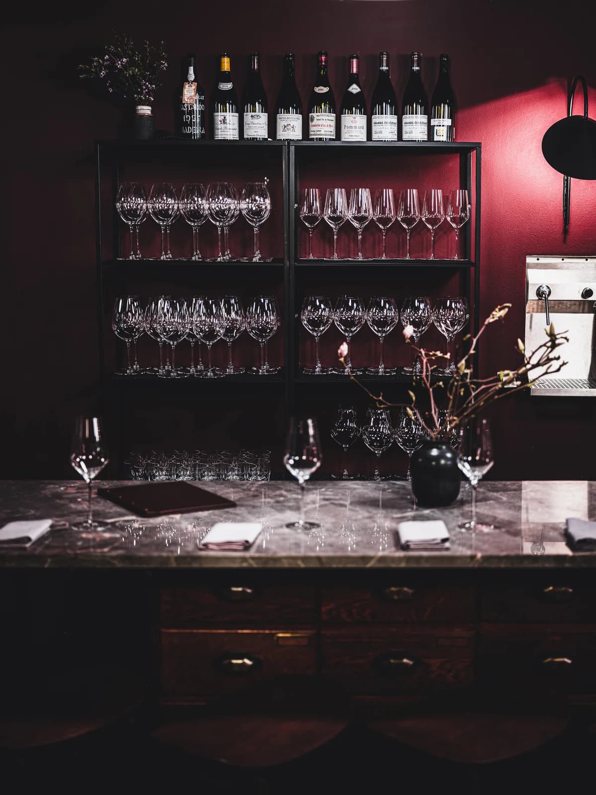Wine glasses and bottles displayed behind the marble bar at The Three Fifty